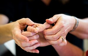 Photo of a therapist's hands supporting someone else's hand.