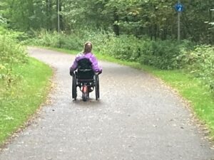 Katherine using her wheelchair on forest path