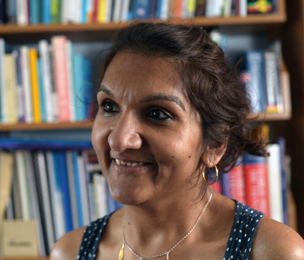 Profile photo of Sonali Shah, a British Indian disabled woman. Books in background.